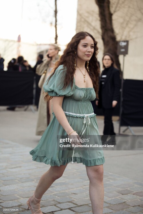 PARIS, FRANCE - MARCH 06: Laufey wears a short green mini dress with a white bow outside the Chloe fashion show during the Womenswear Fall/Winter 2025/2026 as part of Paris Fashion Week on March 06, 2025 in Paris, France. (Photo by Raimonda Kulikauskiene/Getty Images)