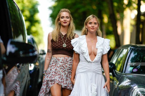 PARIS, FRANCE - JULY 02:  Chiara Ferragni wears a cropped bare belly top, a Chanel necklace, a pleated skirt ;  Valentina Ferragni wears a white low neck dress, outside Giambattista Valli, during Paris Fashion Week Haute Couture Fall Winter 2018/2019, on July 2, 2018 in Paris, France.  (Photo by Edward Berthelot/Getty Images)