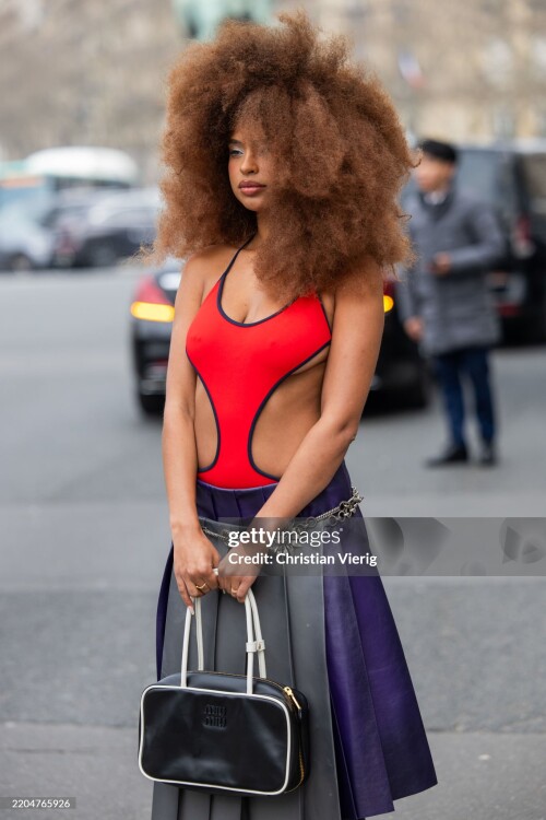 PARIS, FRANCE - MARCH 11: Paola Locatelli wears red cut out shirt, grey pleated skirt, bag outside Miu Miu during the Womenswear Fall/Winter 2025/2026 as part of Paris Fashion Week on March 11, 2025 in Paris, France. (Photo by Christian Vierig/Getty Images)